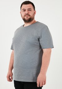 Pilkos trumpomis rankovėmis marškinėliai su apvaliu kaklu ir minkšta, šiek tiek tekstūruota medžiaga. Siluetas laisvas, tinkantis kasdieniams drabužiams.