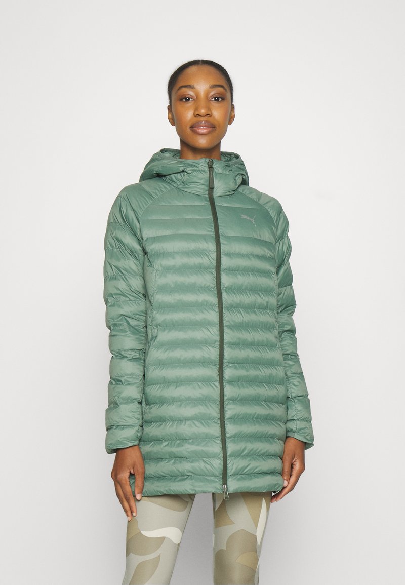 Hellgrüne Pufferjacke mit Kapuze, mit gestepptem Design, durchgehendem Reißverschluss und Logo-Detail. Getragen über gemusterten Leggings.