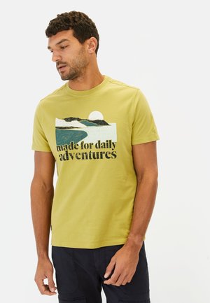 Korte mouwen, ronde hals t-shirt in lichtgroene katoen met een landschapprint van een rivier, bergen en de zon. De tekst luidt "gemaakt voor dagelijkse avonturen."