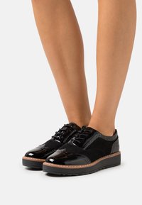 Scarpe stringate in pelle verniciata nera e suede con punta arrotondata, accenti testurizzati, suola spessa e soletta leggermente imbottita.