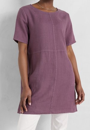 Tuniki z krótkim rękawem sięgającej do kolan, wykonanej z miękkiego lnu w delikatnym fioletowym kolorze; posiada boczne kieszenie, okrągły dekolt oraz subtelne wykończenia szwów.