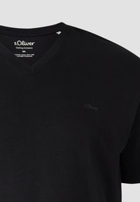 T-shirt noir à col en V en taille 2XL avec un logo s.Oliver subtil sur la poitrine et une étiquette imprimée à l'intérieur du col.
