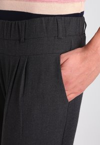 Kolen grijze broek met een gladde textuur, voorzien van een geplooid front, een elastische tailleband en zijzakken.
