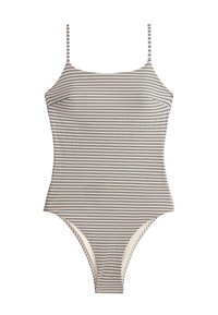 Maillot de bain une pièce rayé avec fines bretelles en lignes horizontales alternées noir et blanc sur fond uni.