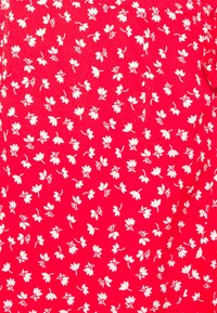 Tissu rouge avec un motif floral blanc répétitif, comprenant de petites fleurs et des feuilles. Texture lisse, design léger.