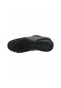 Scarpa sportiva grigia con parte superiore testurizzata, suola in gomma nera con grip rotondi e dettagli blu. Logo Geox visibile sulla suola.