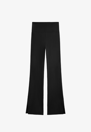 Black pants with a wide-leg design, featuring a high waistband and side slits for ease of movement. Made from a smooth, stretchy fabric.