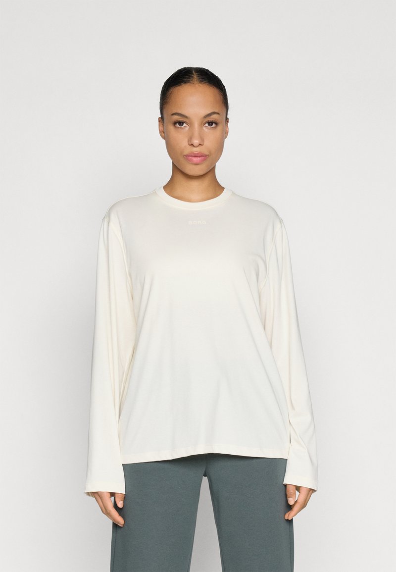 Long-sleeve cream top with a round neckline, made of soft fabric. Features subtle branding in light color on the chest.