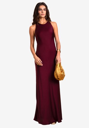 Bordeaux mouwloze maxi-jurk in een strakke, getailleerde stijl, gecombineerd met een gouden trekkoordclutch. Glad materiaal met minimale accenten.