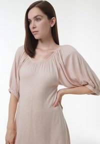 Hellrosa Kleid aus weichem Stoff, mit Rundhalsausschnitt, puffärmeln und gerafftem Detail am Ausschnitt.