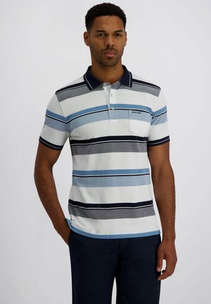Man draagt een polo met korte mouwen met horizontale strepen in wit, blauw, grijs en zwart, gecombineerd met een donkere broek.