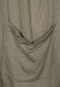 Tessuto verde oliva chiaro con un design testurizzato a maglia che presenta elementi drappeggiati e pieghe morbide, creando un aspetto rilassato.