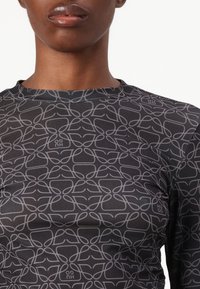 Long-sleeve top in black fabric featuring a grey abstract pattern of interconnected loops, with a high neckline and subtle branding detail.