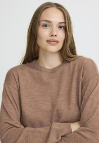 Brązowy sweter z długim rękawem wykonany z miękkiego materiału, z okrągłym dekoltem i luźnym krojem. Gładka faktura z minimalnymi detalami.