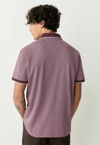 Polo cu maneci scurte dintr-un material texturat de culoare burgundă cu guler și manșete burgundii închis. Prezintă un model subtil și un design clasic.