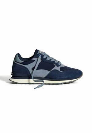 Baskets de sport pour hommes en bleu marine et gris avec des panneaux en tissu mélangé, lacets défaits, et une semelle blanche avec un motif noir.