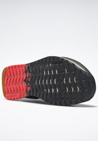 Crna guma na potplatu sportske obuće s crvenim srednjim dijelom, opremljena složenim uzorcima za hodanje za bolju prionjivost i teksturiranom površinom za čvrsto držanje.