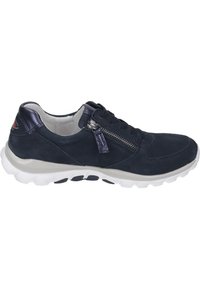 Blauwe suède sneaker met een witte rubberen zool, voorzien van een zijrits, veters en een decoratieve accent op de hiel.