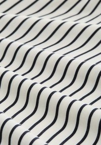 Tessuto bianco con strisce diagonali blu navy, che presenta una superficie liscia con una leggera lucentezza, piegato in onde.