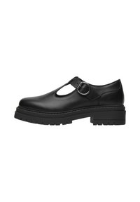 Scarpa in pelle nera con punta tonda, design con ritagli, cinturino alla caviglia e fibbia argentata. Presenta una suola spessa e testurizzata per una maggiore aderenza.