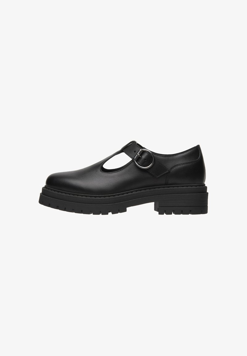 Chaussure en cuir noire avec un bout rond, un design découpé, une bride de cheville et une boucle en argent. Elle dispose d'une semelle épaisse et texturée pour une meilleure adhérence.