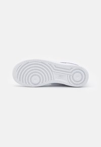 Bílá podrážka tenisek s kruhovým vzorem a kontrastním logem Nike. Texturovaná guma zajišťuje trakci a odolnost. Hladký, čistý design.