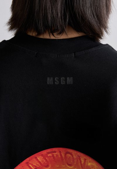Mustra musta T-särk, millel on ümara kujuga punane graafika, millel on reljeefne tekst. Diskreetne bränding "MSGM" tumedamas toonis kaela lähedal. Pehme tekstuur.