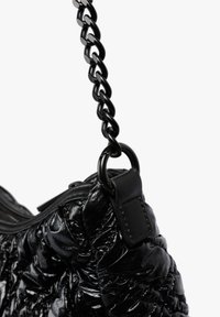Bolso de mano negro brillante acolchado con una asa de cadena negra gruesa unida a anillos de metal y lazos de cuero.