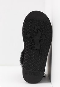 Suela de zapato negra con un patrón de tracción en zigzag, logo de caballo mustang y estrellas, y el texto "MUSTANG" embosado cerca del tacón.
