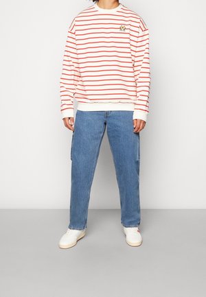 Red and white striped sweatshirt with a logo, paired with blue denim pants and white sneakers. Casual fit, soft texture, relaxed design.