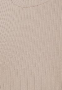 Maglione a coste in beige chiaro con colletto a girocollo aderente. Il tessuto presenta una texture morbida e sottili righe verticali.