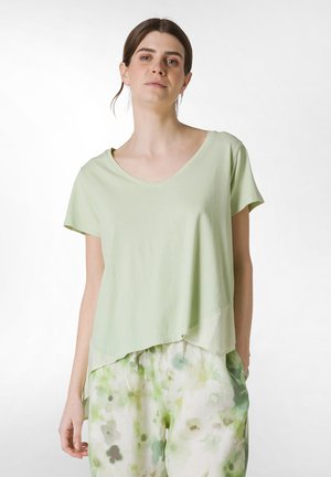 Camiseta verde claro de cuello en V con mangas cortas y un diseño de dobladillo en capas, hecha de una tela suave; combinada con pantalones verde claro con patrón floral.