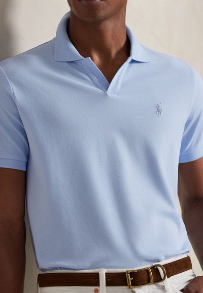 Ανοιχτό γαλάζιο πόλο πουκάμισο από αεριζόμενο ύφασμα, με κλασικό γιακά και διακριτικό κεντημένο λογότυπο στο αριστερό στήθος.