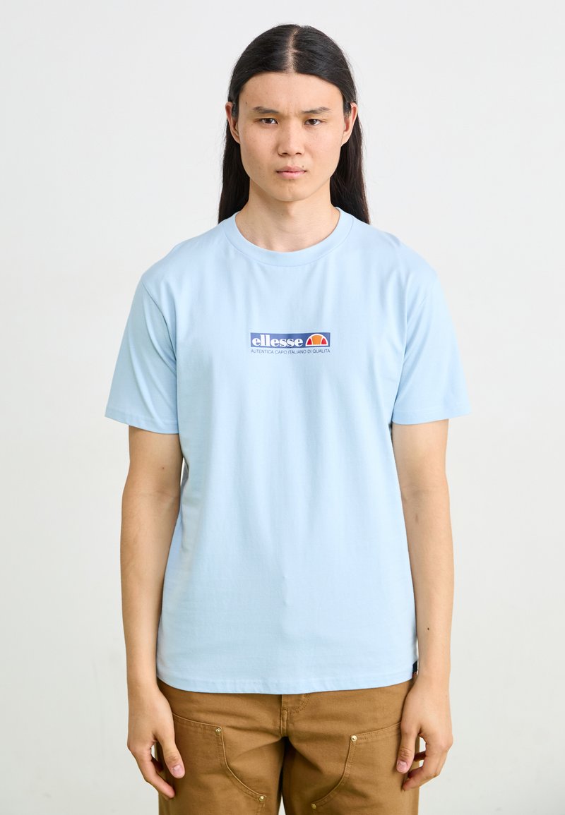 Light blue cotton t-shirt with short sleeves, featuring a graphic logo in red and blue on the chest. Plain design, crew neckline.