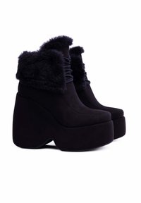 Stivaletti neri con piattaforma, realizzati in un materiale morbido e opaco, con un bordo in pelliccia sintetica, punta arrotondata e un audace design del tacco scultoreo.