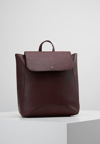 Zaino in pelle bordeaux con una texture liscia, chiusura a patta e manico superiore. Presenta accenti curvi sulla parte frontale.