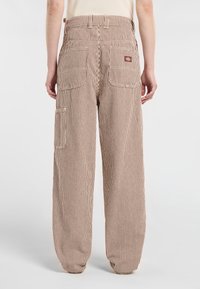 Braun-weiße gestreifte Cargo-Hose mit entspannter Passform, mehreren Taschen und einem Markenpatch am hinteren Bund.