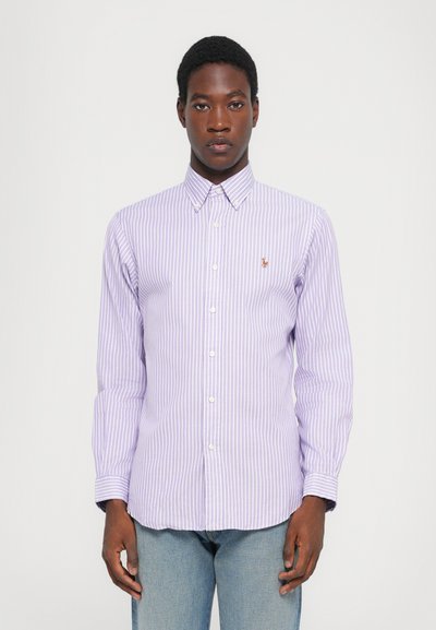 Šviesiai violetinė dryžuota ilgarankovė marškinėliai su sagomis ant apykaklės, baltos sagos ir siuvinėta logotipas kairėje krūtinės pusėje. Medvilnės audinys.