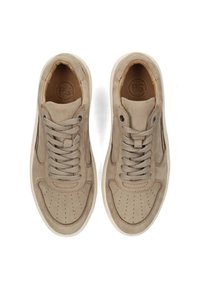 Des baskets beiges avec une texture lisse, un bout rond, un design perforé et de grosses lacets, placées sur un fond blanc uni.