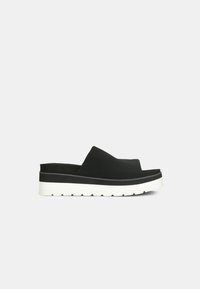 Pantofi platform negri, slip-on, cu un upper neted, talpă albă contrastantă și accente texturate. Dispune de vârful rotund și talpă groasă.