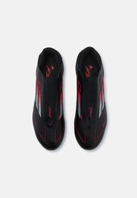 Black soccer shoes with a sleek design, red accents, and striped detailing. Made from textile material with a snug fit and ergonomic shape.