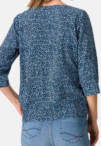 Blå och vit blus med blommigt mönster och trekvartslånga ärmar, tillverkad av lättviktsmaterial. Rundad halslinning och en avslappnad passform.