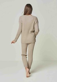 Beige Strick-Loungewear-Set mit geripptem Design, lässigem Pullover mit überschnittenen Schultern und taillierten Hosen mit enganliegenden Bündchen.