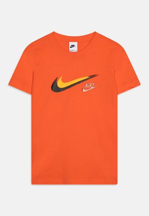 Camiseta de algodón naranja con un gran logo de swoosh de Nike en negro y amarillo y un logo más pequeño en blanco. Diseño de mangas cortas y cuello redondo.