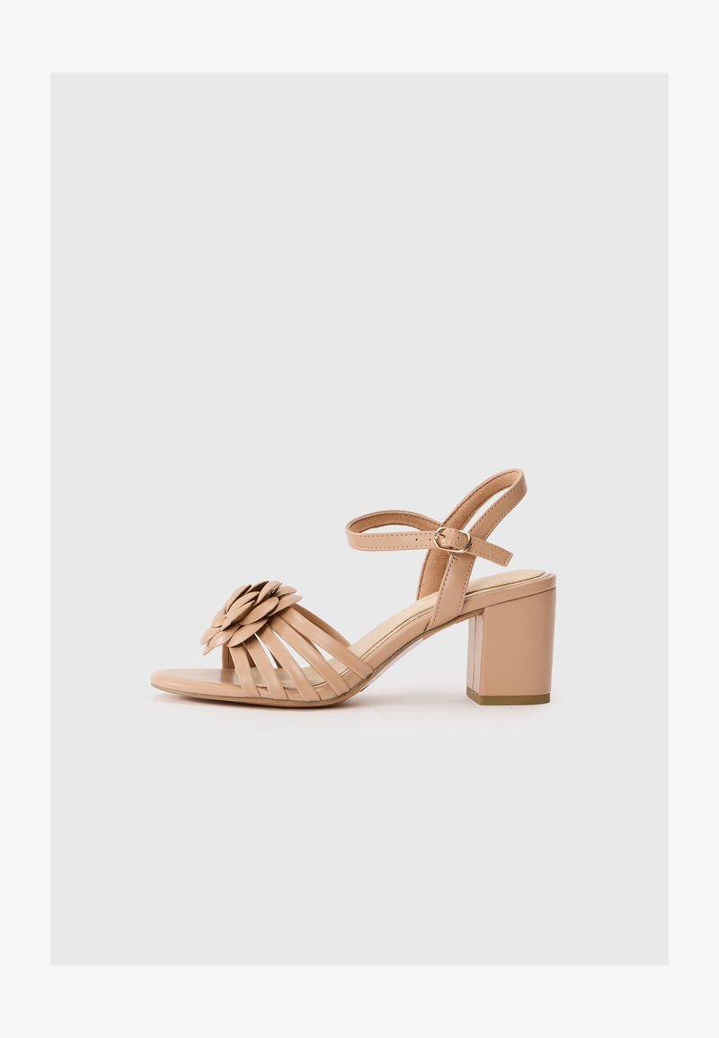 Μπεζ γόβες με ανοιχτό δάχτυλο, διακοσμημένες με λουλουδάτο στοιχείο στην περιοχή των δακτύλων και λουράκι γύρω από τον αστράγαλο με πόρπη. Στρογγυλή χοντρή φτέρνα.