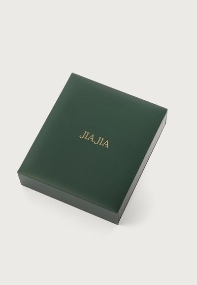 Zöld kartondoboz arany fóliázott "JIA JIA" felirattal, négyzet alakú, sima felület, zárt fedél, minimalista design.
