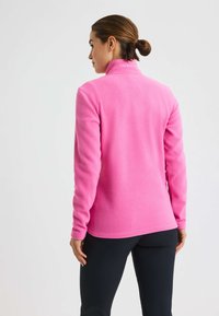 Pullover in pile rosa con colletto alto, maniche lunghe e texture liscia. Presenta un dettaglio con logo vicino al colletto e un orlo dritto.