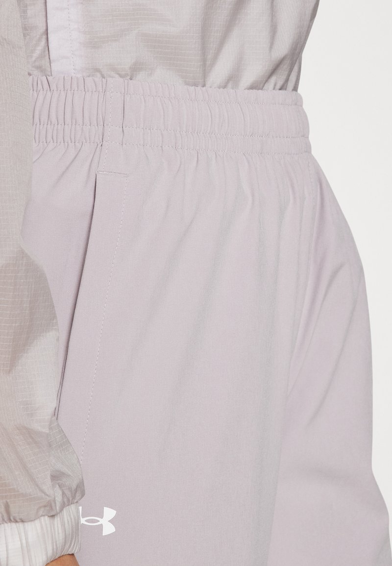 Helle lavendelfarbene Sporthose mit elastischem Bund, weicher Textur und einem kleinen weißen Logo auf der linken Seite. Sie verfügt über seitliche Taschen.