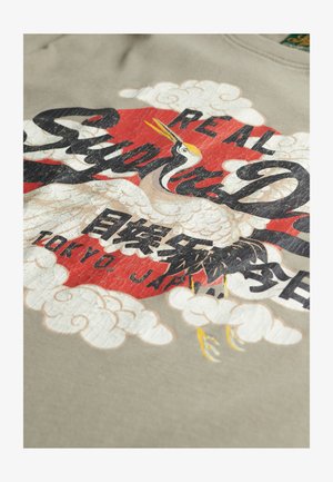 Grauer Kapuzenpullover mit einem grafischen Design eines Kranichs, einem roten Kreis und Text. Der Druck enthält detaillierte Wolken und asiatische Zeichen.