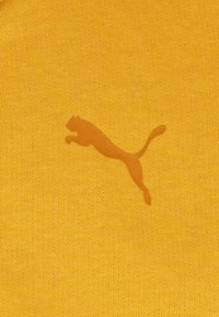 Tessuto giallo con un sottile logo Puma coordinato a forma di gatto che salta. Il materiale ha una morbida texture a maglia.